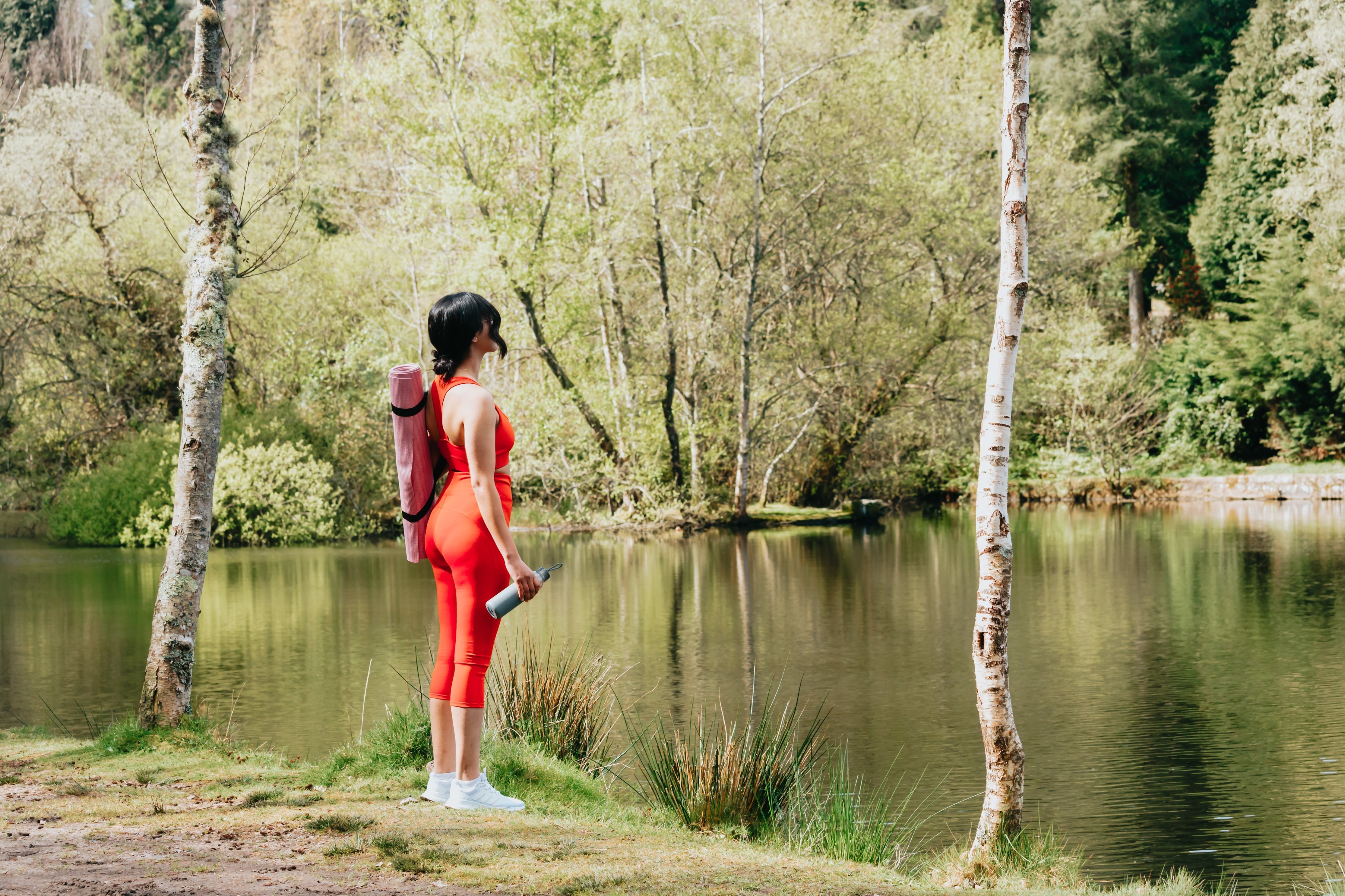 a woman in a red outfit standing next to a lake