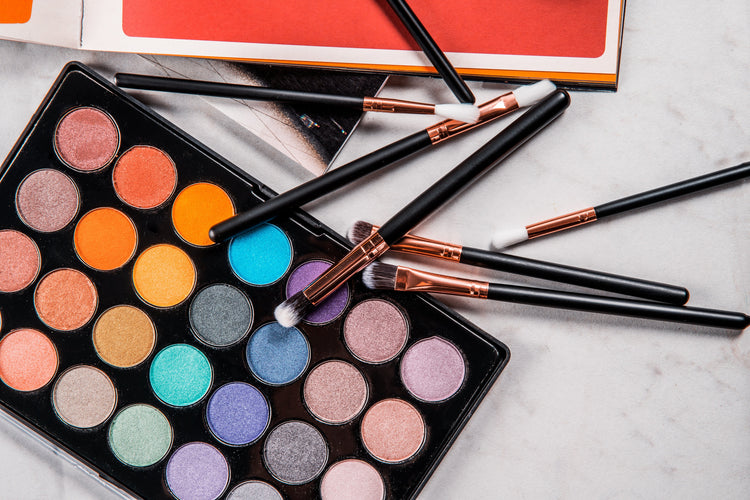 a variety of cosmetics and makeup brushes on a table